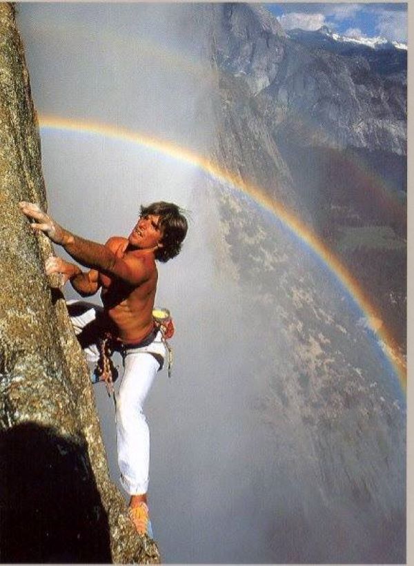 Ron Kauk climbing with rainbow in background