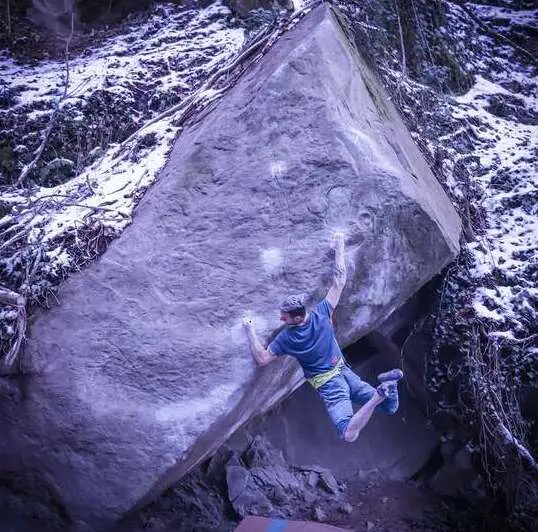 Climber Elias Iagnemma climbing a hard boulder in Italy