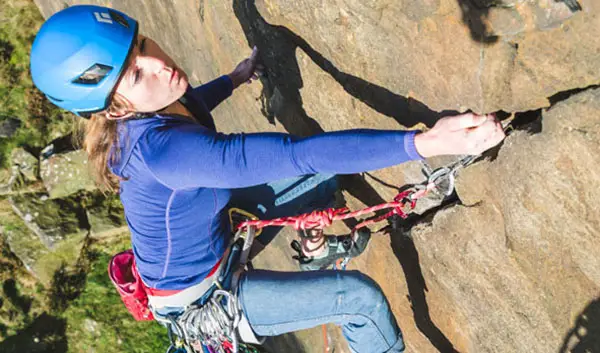 Woman trad climbing pulling on gear