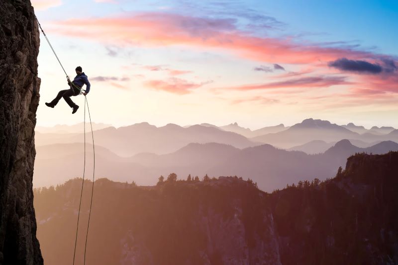 climber rapelling from mountain at sunset