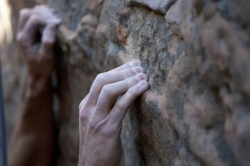 climber crimp climbing with his fingers