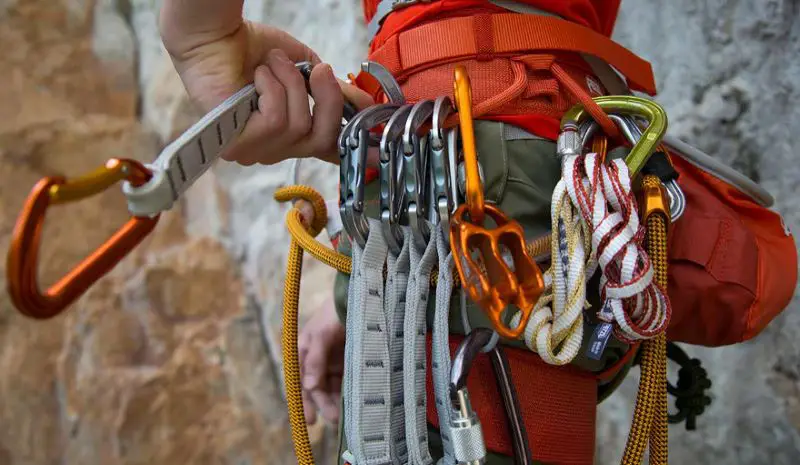 rock climber with all rock climbing essential gear on harness